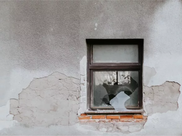a broken window in a cracked wall