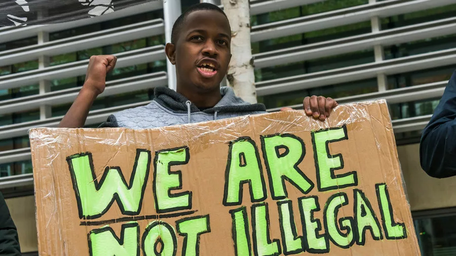 a young boy holding a sign saying "we are not illegal"